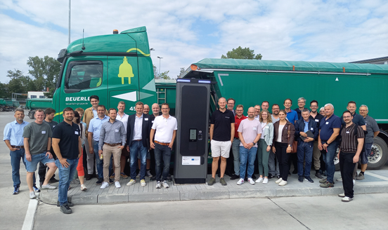 Exkursions-Gruppe vor einem elektrifizierten Lkw mit Ladesäule bei der Firma Beuerlein in Unterfranken